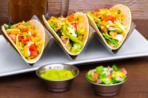 four tacos on a tray with salad in cups at Clarion Inn & Suites Miami International Airport in Miami