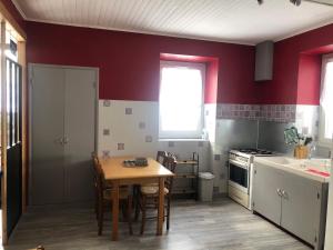 a kitchen with red walls and a wooden table at Maison campagne au col du festre in Le Dévoluy