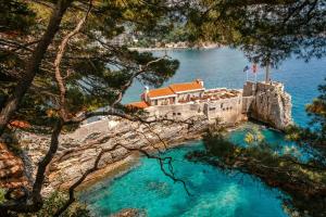 a building on a cliff next to the water at Luxury Apartments Queen in Petrovac na Moru