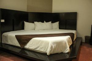 Hotel Cancalli Business & Suites في Tlaxcala de Xicohténcatl: غرفة نوم مع سرير كبير مع اللوح الأمامي الأسود