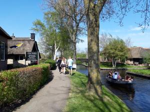 personas caminando por una acera junto a un canal con un barco en Appartement Het Kleine Huisje met bedstee, en Giethoorn