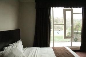 Hotel Cancalli Business & Suites في Tlaxcala de Xicohténcatl: غرفة نوم بسرير ونافذة كبيرة