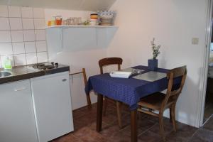 een keuken met een tafel met een blauwe tafeldoek bij Appartement Het Kleine Huisje met bedstee in Giethoorn