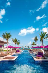 a resort swimming pool with chaise lounges and palm trees at Planet Hollywood Adult Scene Cancun, An Autograph Collection All- Inclusive Resort - Adults Only in Cancún