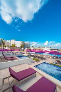 a resort pool with purple lounge chairs and umbrellas at Planet Hollywood Adult Scene Cancun, An Autograph Collection All- Inclusive Resort - Adults Only in Cancún