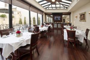 a restaurant with white tables and chairs and windows at Hotel Sainte Jeanne in Mar del Plata