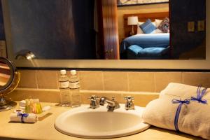 a bathroom with a sink and a mirror and a bed at Hotel Boutique Casa Catrina in Oaxaca City