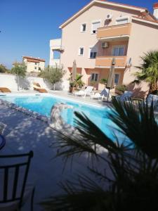 a swimming pool in front of a building at Apartments Zeneral in Novalja