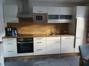 a kitchen with white cabinets and a sink and a microwave at Haus Stefan in Neustift im Stubaital