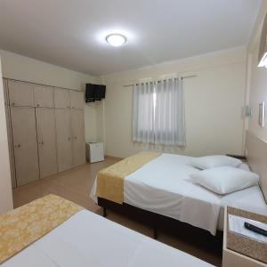 Un dormitorio con dos camas y un televisor. en Grand Ville Hotel, en São Lourenço