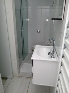 a white bathroom with a sink and a shower at Pousada Alvorada Brotas - e agendamento das atividades turísticas in Brotas