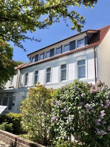 a white house with flowers in front of it at Strandloft Drei Norderney in Norderney