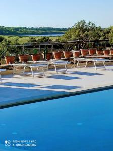 une rangée de tables blanches assises à côté d'une piscine dans l'établissement La Trottoria Agriturismo, à Otrante