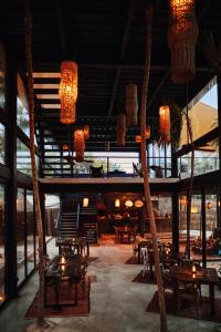 un ristorante con tavoli, sedie e lampadari a braccio di Our Habitas Tulum a Tulum