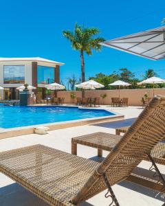 un complejo con una piscina con una silla de mimbre en Pontal Praia Hotel en Porto Seguro