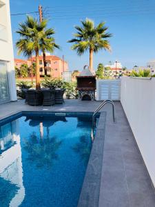 a swimming pool with a grill and palm trees at Mobina Villas in Larnaka