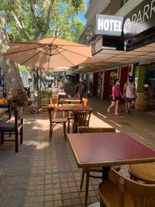 um café ao ar livre com mesas e cadeiras e um guarda-sol em Palace Hotel Mendoza em Mendoza