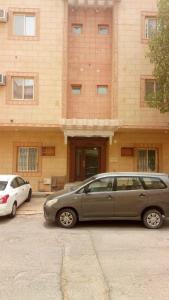 two cars parked in a parking lot in front of a building at الخزامى in Al Ahsa