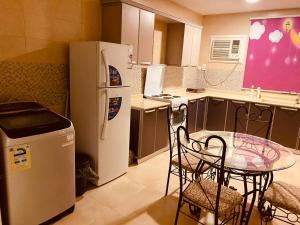 a kitchen with a glass table and a refrigerator at الخزامى in Al Ahsa