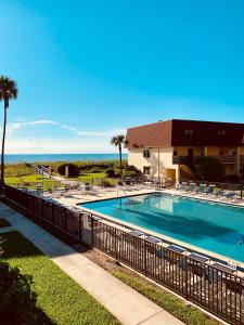 a swimming pool with chairs and the ocean in the background at Beautiful Ocean view Townhouse in Cocoa Beach