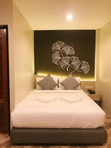 a bedroom with a white bed with a black wall at SJ Miracle Hotel in Hat Yai