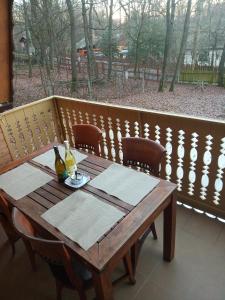 a wooden table with a bottle of wine on a balcony at Őzike-Lak a Börzsönyben in Kismaros
