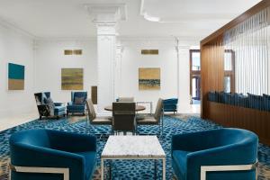 a waiting room with blue chairs and a table at Club Quarters Hotel Downton, Houston in Houston
