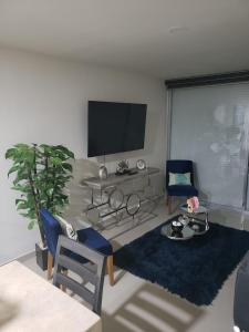 マサトランにあるDepartamento en malecon Portico Beachのリビングルーム(テレビ、テーブル、椅子付)