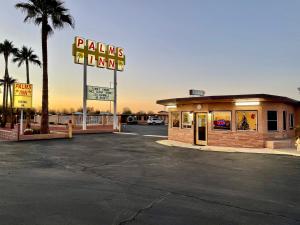 a parking lot with a pizza shop and a sign at Palms Inn in Gila Bend