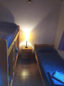 Una pequeña habitación con dos camas y una lámpara. en Duplex cerca del Mar en Las Toninas, en Las Toninas