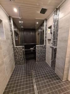een badkamer met een douche en een tegelvloer bij Villa white Lion in Pusula