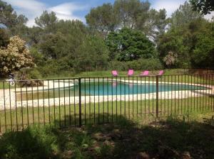 una valla con sillas rosas y una piscina en La Maison R, en Pignans