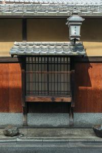 un banco con una luz en el lateral de un edificio en Toshiharu Ryokan, en Kioto
