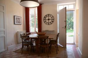 a dining room with a table and chairs and a clock at La Maison R in Pignans