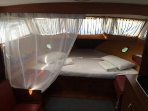 een klein bed in een kleine kamer met gordijnen bij Home Boat in Badalona