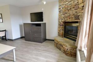 a living room with a stone fireplace and a television at Best Western Cades Cove Inn in Townsend +7 photos