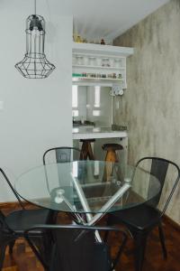mesa de cristal con sillas negras y cocina en Departamento centro Cordoba capital en Córdoba