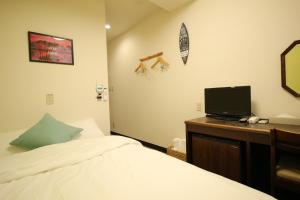 a bedroom with a bed and a desk with a television at Okubo Hotel Hawaii in Tokyo
