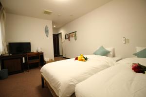 a hotel room with two beds and a television at Okubo Hotel Hawaii in Tokyo