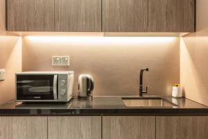 um balcão de cozinha com um micro-ondas e um lavatório em Hotel Calmo Bugis em Singapura