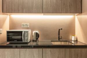 a kitchen counter with a microwave and a sink at Hotel Calmo Bugis in Singapore