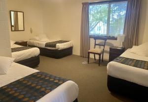 a hotel room with two beds and a desk at Grosvenor Court Apartments in Hobart