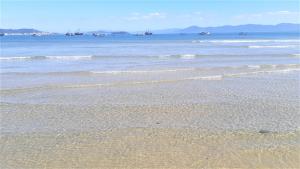 una playa con pequeñas olas y barcos en el agua en Residencial Las Flores, en Florianópolis