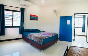 a bedroom with a bed and a blue door at บ้านนอกเมืองรีสอร์ต BaanNokMueang in Phayao