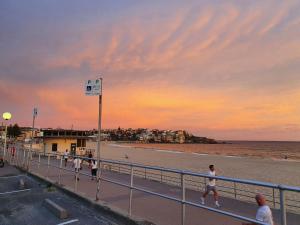 een groep mensen die bij zonsondergang op het strand lopen bij Bondi Beach Backpackers in Sydney