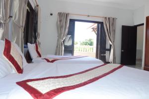 2 camas blancas en una habitación con ventana en DTC Hotel, en Da Nang