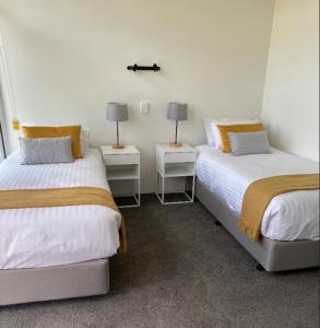 two beds in a room with two lamps on tables at Orford Blue Waters Hotel in Orford