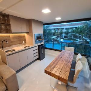 een keuken met een houten tafel en een groot raam bij Praia dos Carneiros Flat 207 A - Carneiros Beach Resort in Tamandaré