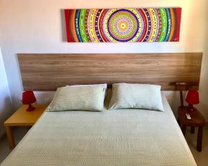 - un lit avec deux oreillers et un tableau au-dessus dans l'établissement Flat Cumaru ap 210 TEMPORADANOFRANCES Localização privilegiada e conforto, à Praia do Frances