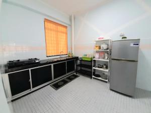 Il comprend une cuisine équipée d'un réfrigérateur en acier inoxydable et une fenêtre. dans l'établissement Huda Homestay @ Port Dickson, à Port Dickson